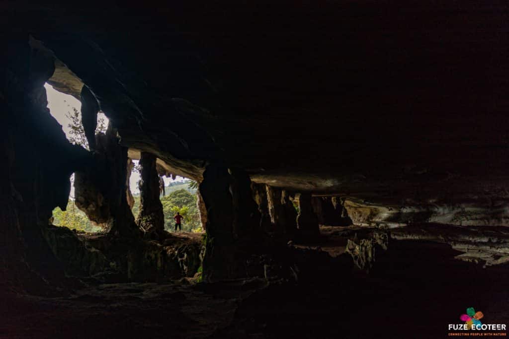 distant silhouette standing and looking out from a large limestone cave opening